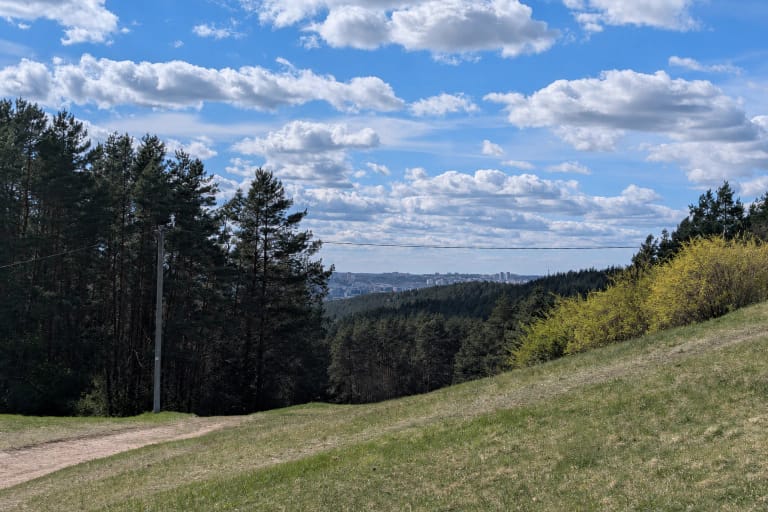 Rokantiškių regyklos žolėtas buvusios slidinėjimo trasos šlaitas, pušynai, seno keltuvo stulpas ir Vilniaus panorama