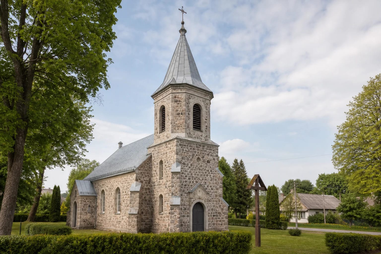 Rūdiškės Sacred Heart of Jesus Church in pale stone masonry with a central tower in a green churchyard