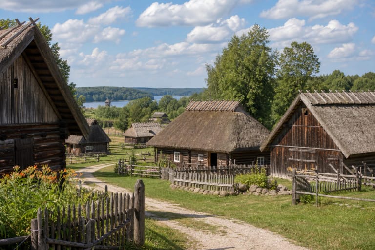 Rumšiškių atviras etnografijos muziejus su medinėmis šiaudiniais stogais dengtomis sodybomis, tvoromis ir Kauno marių kraštovaizdžiu