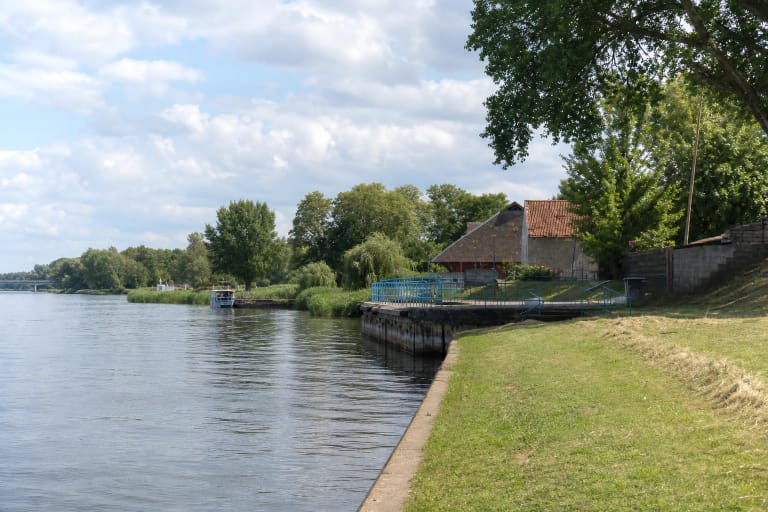 Rusnė Pier on the Atmata, with a low concrete quay, blue railings, and the flat delta landscape