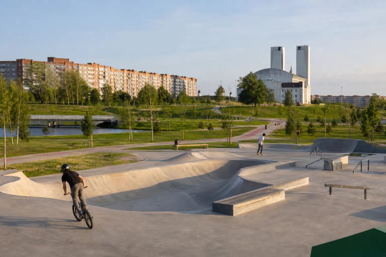 Betoninis riedlenčių ir BMX parkas Sąjūdžio parke, apsuptas žalių vejų, takų ir pietinės Klaipėdos daugiabučių