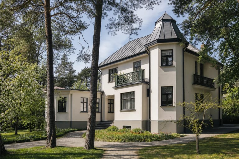 Balta Salomėjos Nėries ir Bernardo Bučo vila su tamsiu stogu ir žaliu balkonu tarp Palemono pušų