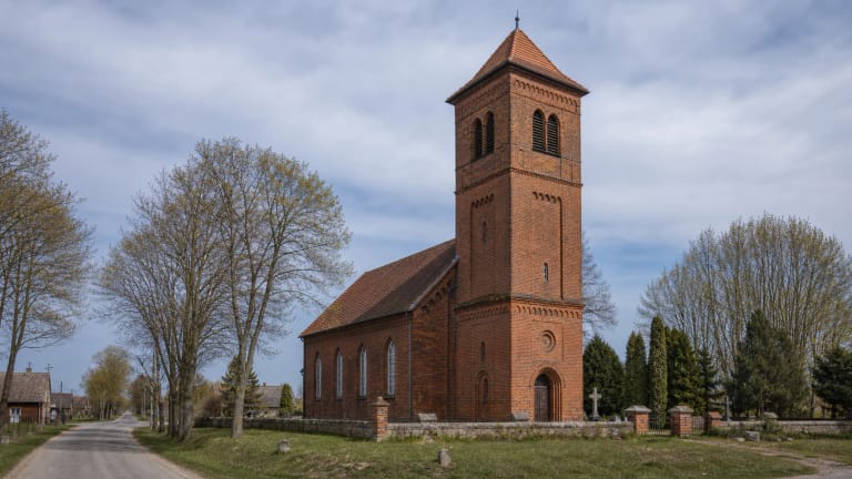 Saugų evangelikų liuteronų bažnyčia su raudonų plytų fasadu ir nedideliu bokšteliu