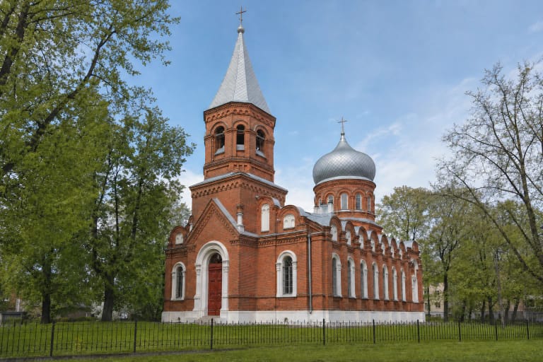 Šiaulių Šv. Jurgio bažnyčios raudonų plytų fasadas, aukštas bokštas ir sidabrinis svogūniškas kupolas