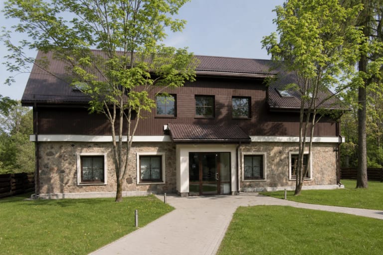 Restauruotas Sirvėtos regioninio parko lankytojų centro svirnas su akmens mūro pirmu aukštu, tamsia medine apdaila ir trinkelėmis grįsta prieiga