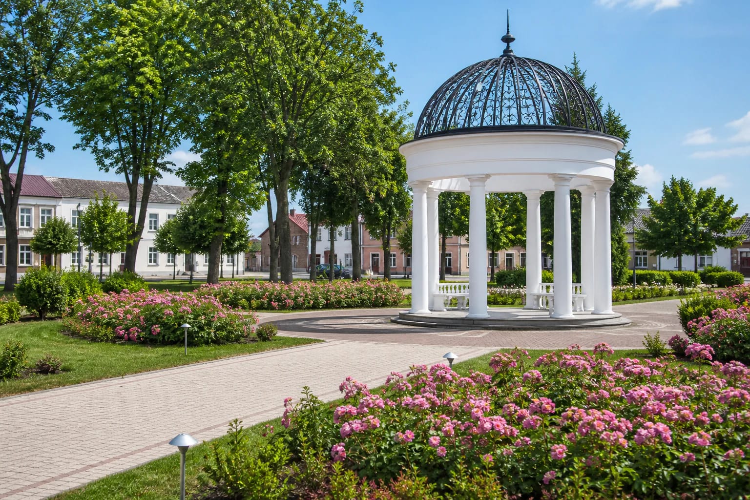 White rotunda with a dark dome in Širvintos Jaunimo Garden among roses and green paths