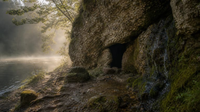 Skališkės Cave on the Neris bank with a dripping spring and forest shadows
