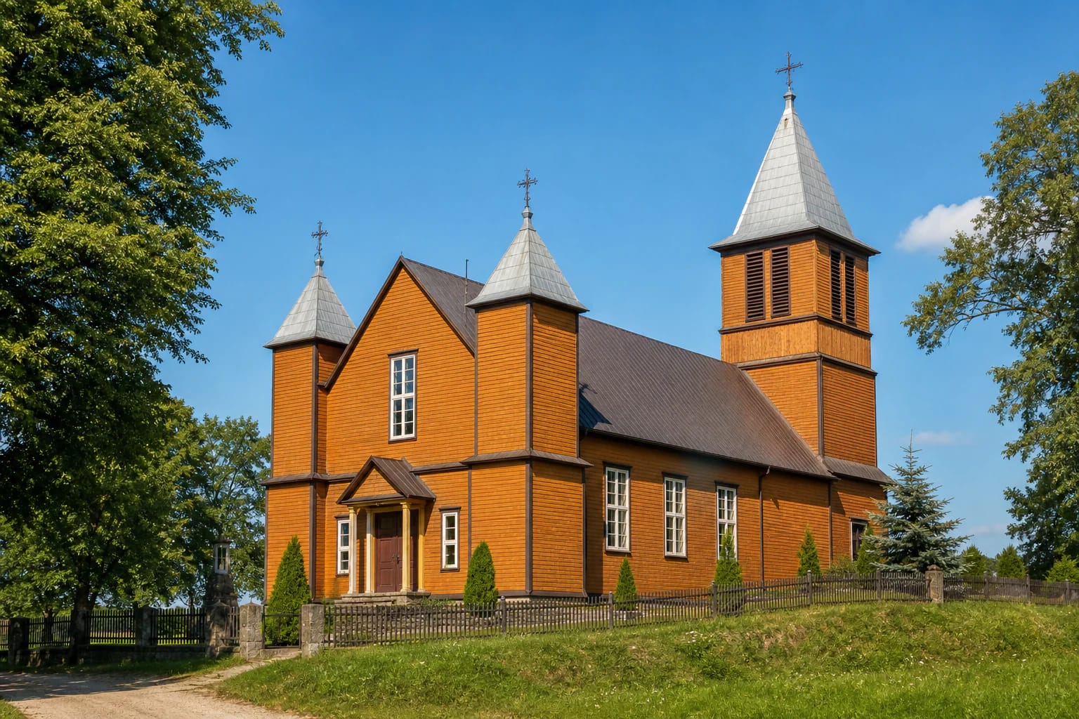 Oranžinė medinė Slavikų Šv. Onos bažnyčia su dviem bokšteliais, varpine ir žaliu šventoriumi