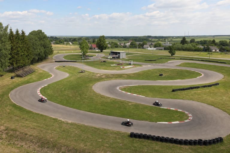 Iš aukščiau matoma vingiuota Smalininkų kartodromo asfalto trasa su kartingais, padangų atitvarais ir kuklia tribūna