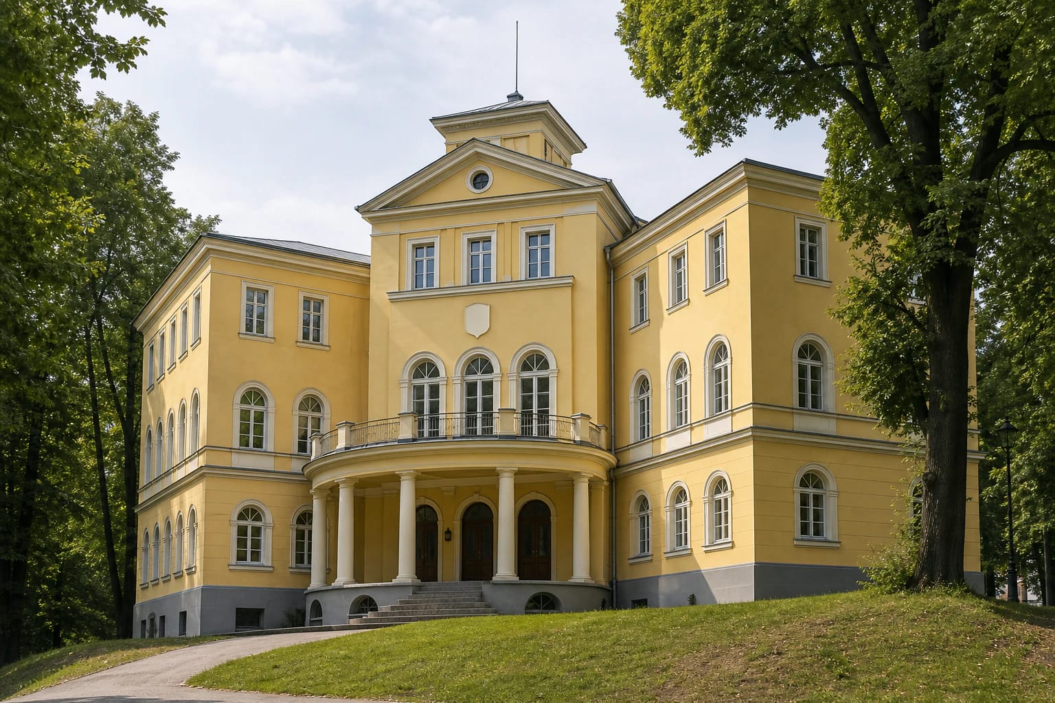 Yellow historicist facade of the Neo-Lithuania Student Corporation Palace in Kaunas with a columned terrace, balcony, pediment, small tower, and trees on Parodos Hill
