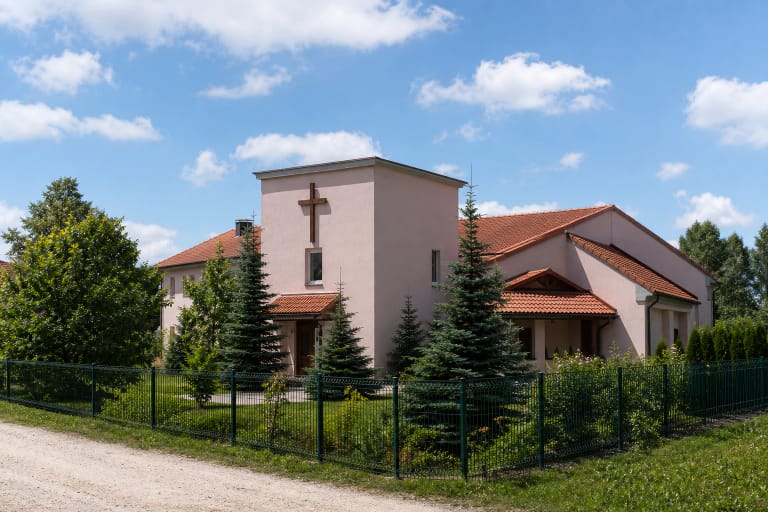 Rožinio tinko Šv. Klaros seserų vienuolynas Kretingoje su raudonų čerpių stogais, kryžiumi ir eglių sodu