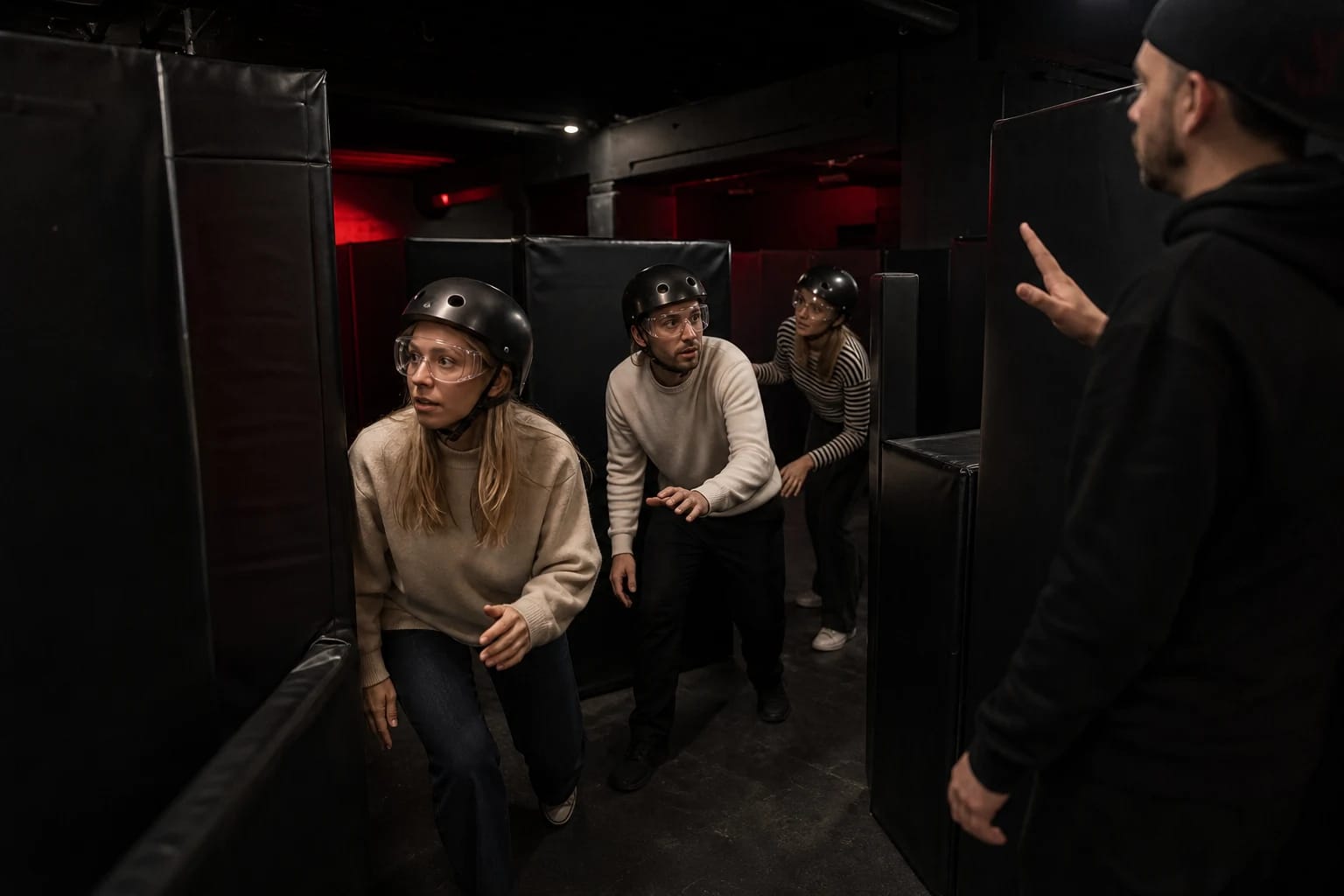 Players wearing protective glasses and helmets move through a dark labyrinth of padded walls