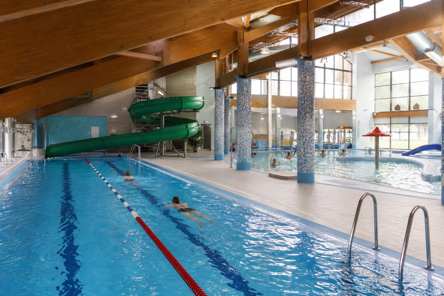 Swimming lanes, slide and timber roof beams inside Tauragė Swimming Pool