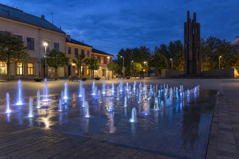 Tauragės muzikinio fontano šviesomis apšviestos vandens srovės Atgimimo aikštėje vakare