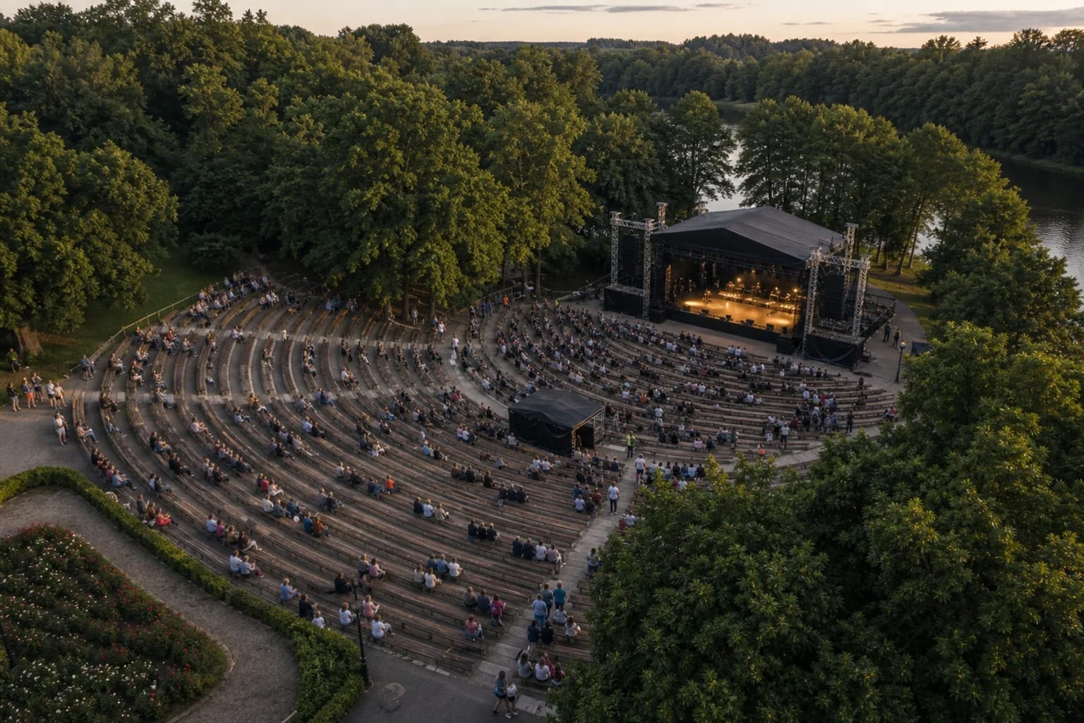 Temporary stage and audience lawn at Tauragė Summer Stage beside the Jūra in the evening