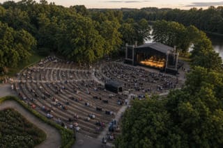 Temporary stage and audience lawn at Tauragė Summer Stage beside the Jūra in the evening
