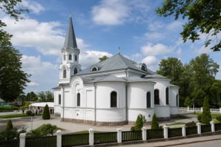 Белая Малая церковь Тельшяй на Вильнюсском холме: высокая башня с серым шпилем и три полукруглые апсиды