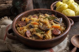Braised sauerkraut with carrots, onions, mushrooms, and smoked sausage in a clay dish