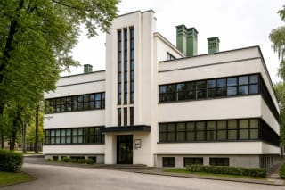 White functionalist facade of the Research Laboratory in Kaunas with ribbon windows and green ventilation turrets on the roof