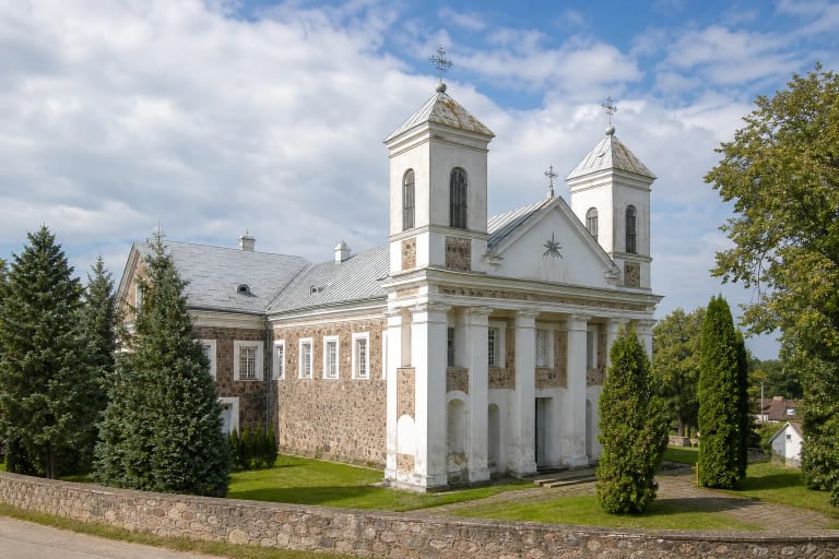 Valkininkų Švč. Mergelės Marijos Apsilankymo bažnyčios lauko akmenų fasadas, du balti bokštai ir pilki skardiniai stogai