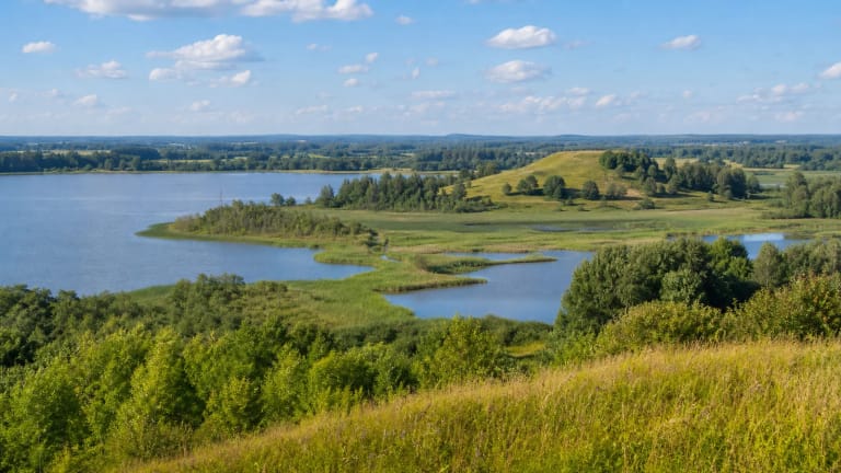 Varnių regioninio parko kalvotas Žemaitijos kraštovaizdis su ežeru, pelke ir tolima piliakalnio panorama