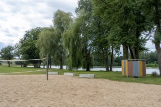 Velžio paplūdimio smėlio aikštelė su tinklinio tinklu, spalvinga persirengimo kabina ir Nevėžio pakrante