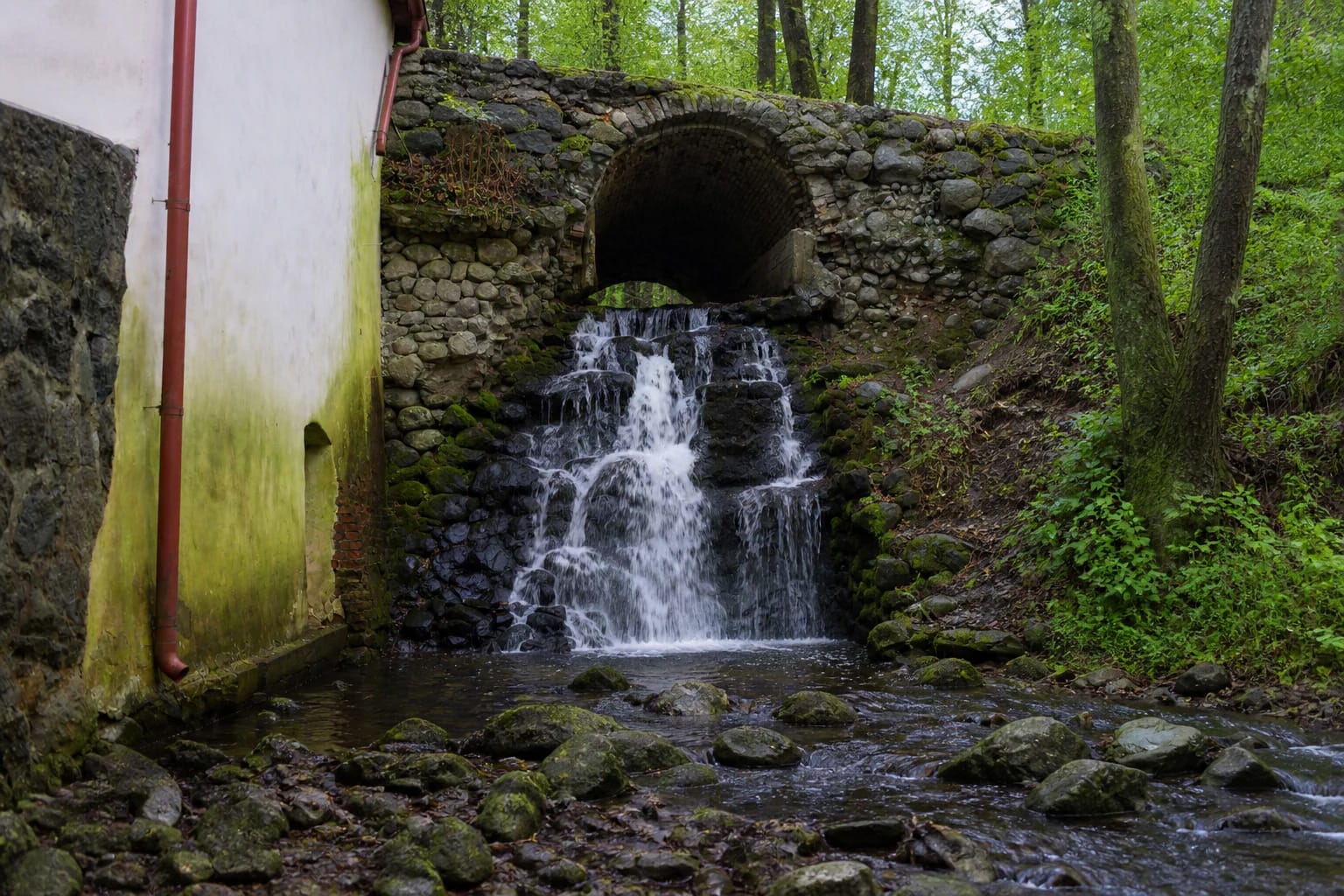 Verkiai Park Waterfall cascading between mossy stones and trees