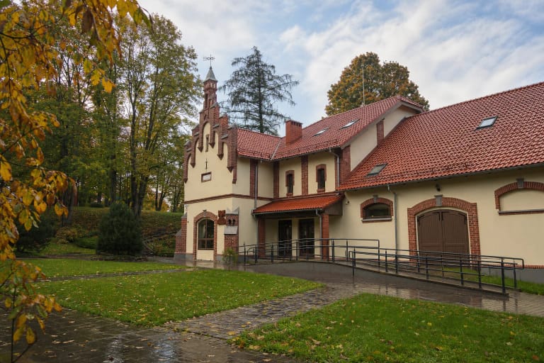 Restauruotos gelsvos Vėžaičių dvaro arklidės su raudonų plytų apvadais, laiptuotu frontonu ir čerpių stogu parke