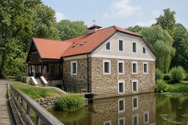 Stone Vilkėnų Watermill with a red roof beside a water channel