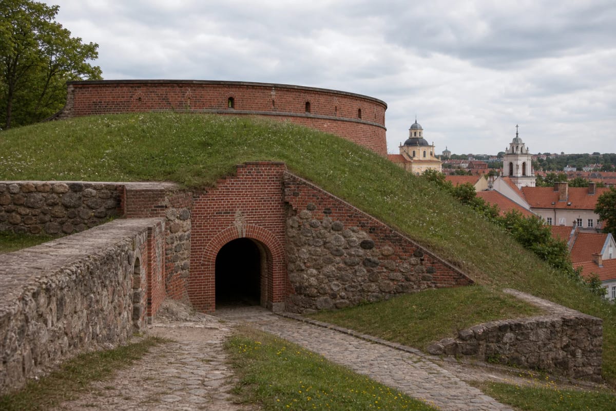 Masonry and grassy rampart of the Bastion of the Vilnius Defensive Wall with an old-town panorama from Bokšto Hill