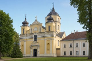 Жёлтый двухбашенный фасад Вильнюсской церкви Спасителя и высокий восьмигранный купол среди зелени Антакальниса