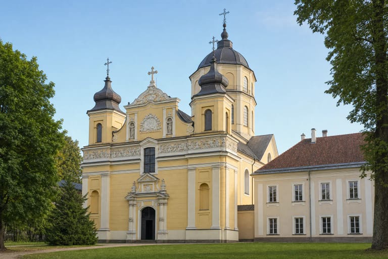 Gelsvas dvibokštis Vilniaus Išganytojo bažnyčios fasadas ir aukštas aštuonkampis kupolas Antakalnio žalumoje
