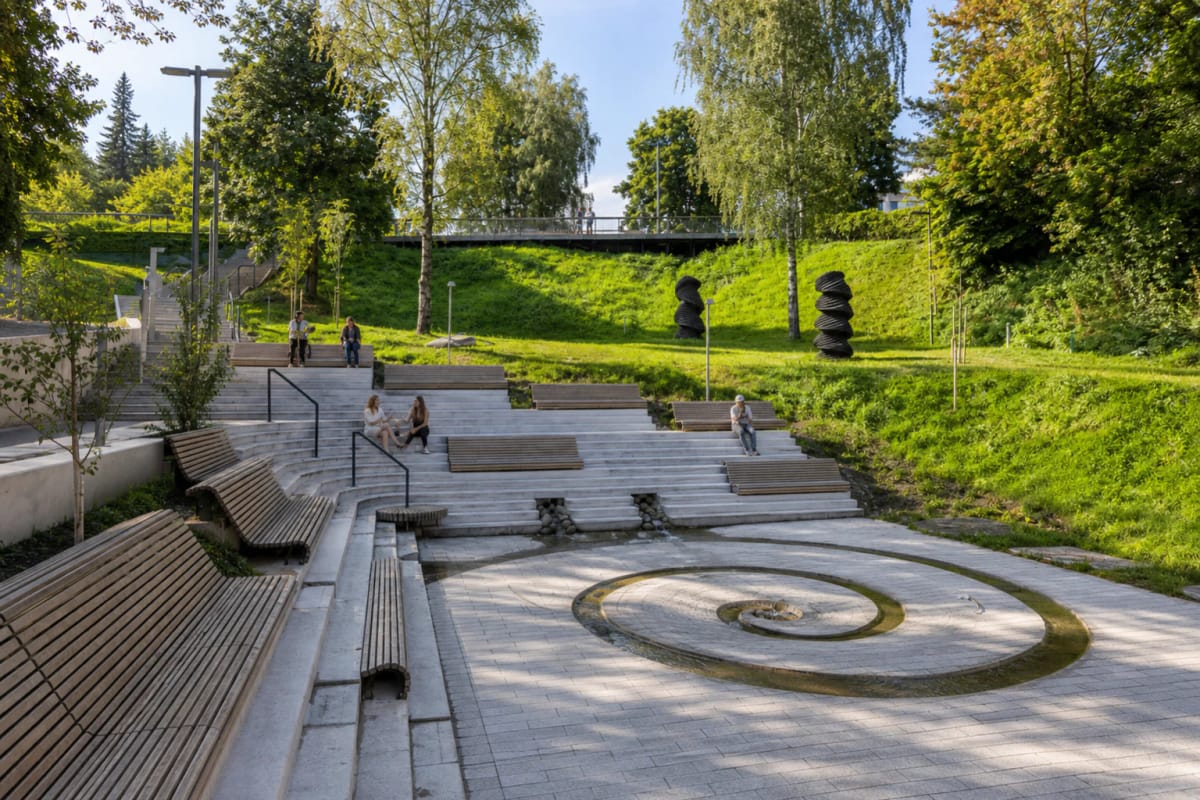 Spiral water basin, terraced steps, and wooden benches on the green Vilnius slope of Vingriai Springs Square