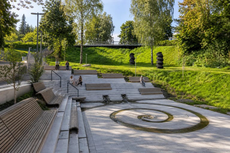 Vingrių šaltinių skvero spiralinis vandens baseinėlis, terasiniai laiptai ir mediniai suolai žaliame Vilniaus šlaite