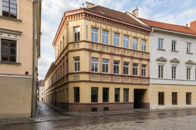 Ochros ir rausvo tinko Vokiečių 6 pastatas Vilniaus senamiestyje su įėjimo arka dešinėje
