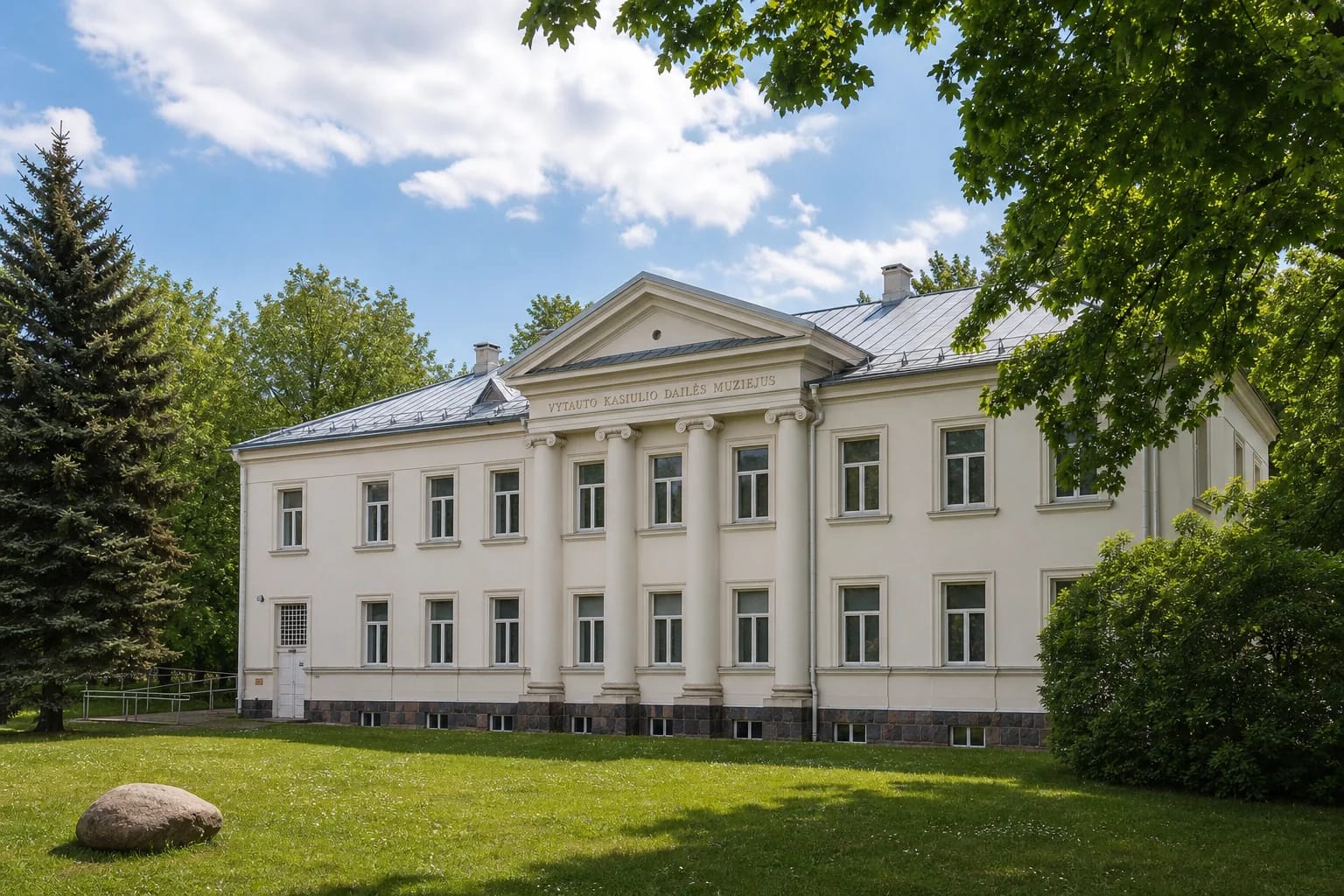 Светлый неоклассический фасад музея искусств Витаутаса Касиулиса с четырьмя полуколоннами и треугольным фронтоном