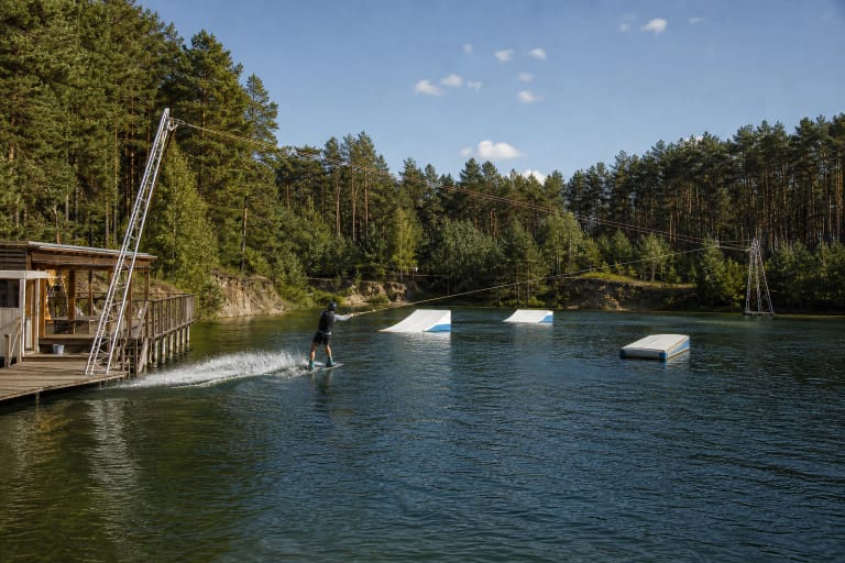 Vandenlentininkas Wakepark Palanga karjero trasoje tarp pušų, lynų bokštų ir baltų figūrų