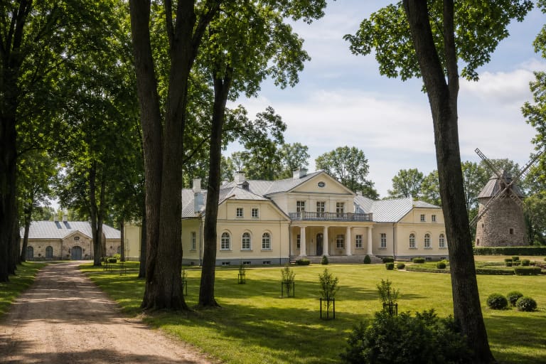 Light-coloured Žagarė Manor palace, park lawn, and avenue of old trees