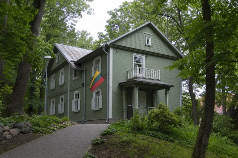 Green wooden Holocaust Exhibition house on Pamėnkalnio Street among mature trees in Vilnius