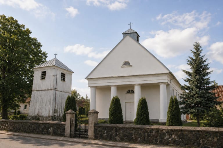 White Žemaičių Naumiestis Evangelical Lutheran Church with a four-column portico, roof turret, and timber belfry behind a fieldstone wall