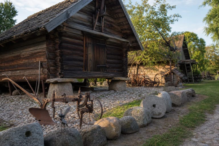 Žemdirbio muziejaus rąstinė klėtis, seni plūgai ir girnapusės Truikinų sodybos kieme