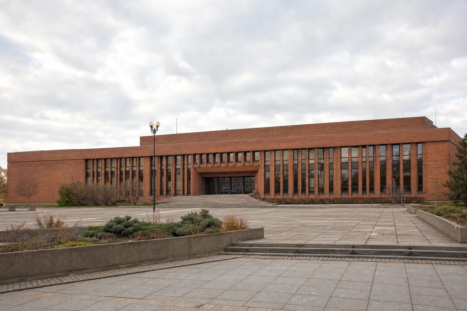 Краснокирпичный модернистский фасад Дворца рыбаков и широкая площадь на проспекте Тайкос в Клайпеде