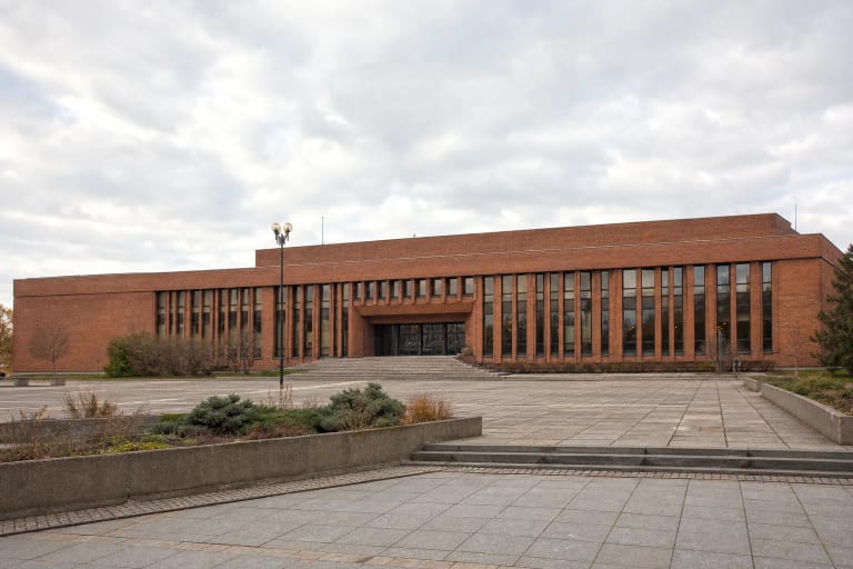 Red-brick modernist facade of Žvejų Rūmai and its broad plaza on Taikos Avenue in Klaipėda